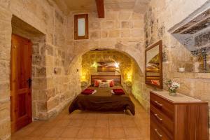 a bedroom with a bed in a stone wall at Razzett Tuta Holiday Home in Kerċem