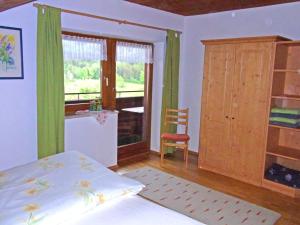 1 dormitorio con 1 cama, 1 silla y 1 ventana en Ferienwohnung Bauernhaus Kailhof en Aschau im Chiemgau