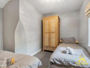 バクストンにある30a Peak Mews - Spacious 3 bedroom apartment at the heart of Buxtonのベッドルーム1室(ベッド2台、木製キャビネット付)