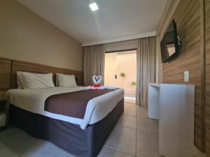 sypialnia z dużym łóżkiem i telewizorem w obiekcie Pousada Recanto do Lobo w mieście Porto de Galinhas