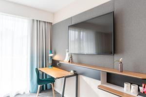 Habitación de hotel con escritorio y TV en la pared en Holiday Inn - Bordeaux-Merignac, an IHG Hotel, en Mérignac