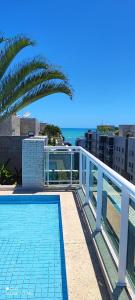 un balcón con una piscina y una palmera en Beira Mar Praia Jatiúca, en Maceió