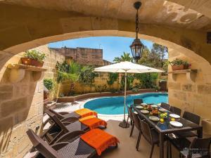 a patio with a table and chairs and a pool at Ta' Majsi Holiday Home in Xlendi