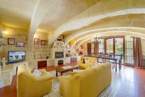 a living room with yellow furniture and a stone wall at Ta' Majsi Holiday Home in Xlendi