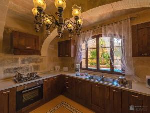 a kitchen with wooden cabinets and a sink and a window at Ta' Majsi Holiday Home in Xlendi