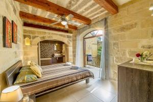 a bedroom with a large bed in a stone wall at Ta' Majsi Holiday Home in Xlendi