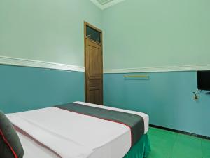 1 dormitorio con cama y pared azul en Collection O 91914 Hotel Citra Dewi 2 Int's, en Semarang