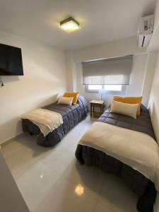 a bedroom with two beds and a tv on the wall at HAUS APARTAMENTOS in Salta