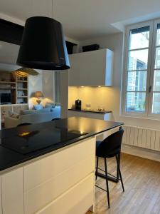 a kitchen with a black counter top and a living room at Luxe et Charme - Le Carré Saint-Silain in Périgueux