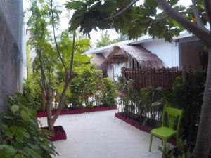 un cortile di una casa con una sedia verde e alberi di Maafushi View a Maafushi
