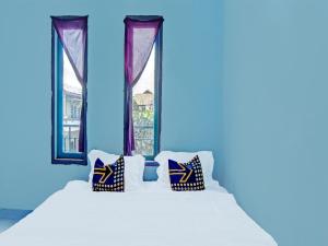 een slaapkamer met een bed met kussens en een raam bij SPOT ON 91918 Najla Guest House Syariah in Parit