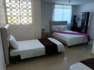 1 dormitorio con 2 camas y ventana en buenavista class, en Barranquilla
