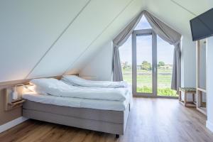 a bedroom with a bed and a large window at Duyndomein Noordwijk in Noordwijk