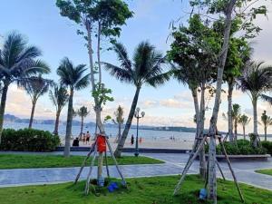 下龍灣的住宿－Rio Ha Long Homestay - Green Bay Garden A1605，享有棕榈树公园和海滩的景致