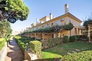 una casa grande con arbustos y árboles delante de ella en Chalet Cormoran, en Chiclana de la Frontera