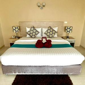 a bedroom with a large bed with two red roses on it at Thipurai City Hotel in Hua Hin