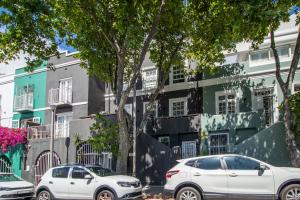 Cape Town的住宿－Cape Finest Guest House located in De Waterkant，两辆白色汽车停在大楼前