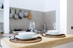 einen Tisch mit zwei weißen Schalen und Weingläsern in der Unterkunft Apartment Don Giuliano Centro in Lecce