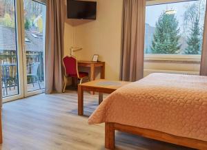 Habitación de hotel con cama, escritorio y ventana en AM BERG Hotel en Herzberg am Harz