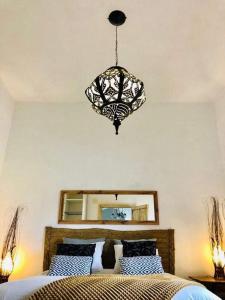 a chandelier hanging over a bed in a bedroom at El Quinto de Luciañez in Ventas con Peña Aguilera