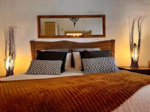 1 dormitorio con cama con almohadas y espejo en El Quinto de Luciañez en Ventas con Peña Aguilera