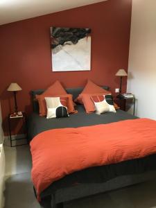 a bedroom with a bed with orange sheets and pillows at La possibilité d’une île in Boyardville