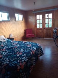 a bedroom with a bed and a red chair at Cycling Hostel Piedra Azul in Puerto Montt