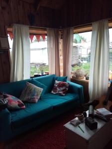 a blue couch in a living room with windows at Cycling Hostel Piedra Azul in Puerto Montt