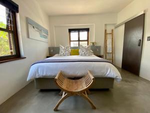 - une chambre avec un grand lit et un fauteuil en bois dans l'établissement Stay On Main Plett - Contemporary 2-Bedroom Apartment, à Plettenberg Bay