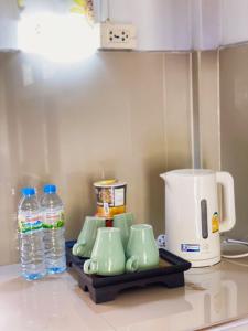 una encimera de cocina con tazas verdes y botellas de agua en บ้านสวนจันทร์เจ้า en Wang Nam Khieo
