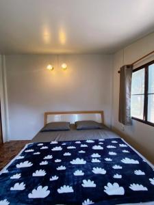 um quarto com uma cama com um cobertor azul com nuvens em บ้านสวนจันทร์เจ้า em Wang Nam Khieo