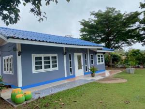 una casa azul y blanca con patio en บ้านสวนจันทร์เจ้า, en Wang Nam Khiao