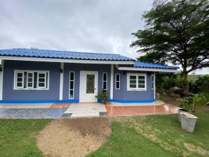 a blue house with a tree in front of it at บ้านสวนจันทร์เจ้า in Wang Nam Khieo