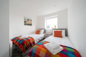two beds in a room with white walls at Links Loft -2 bed apartment minutes from Aberdeen beach in Aberdeen
