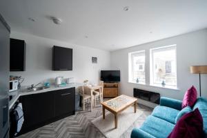 a living room with a blue couch and a kitchen at Links Loft -2 bed apartment minutes from Aberdeen beach in Aberdeen