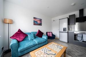 Una sala de estar con un sofá azul y una mesa. en Links Loft -2 bed apartment minutes from Aberdeen beach, en Aberdeen