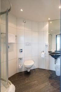 a white bathroom with a toilet and a sink at Aarau West Swiss Quality Hotel in Oberentfelden