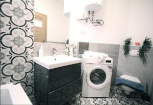 Zamojska Residence Apartments في لوبلين: حمام مع غسالة ومغسلة