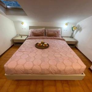 a large pink bed with a tray of fruit on it at Milordo Gubbio Apartment in Gubbio