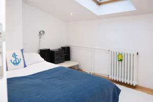 Lovely 2BDR Loft Apartment في سراييفو: غرفة نوم بسرير وبطانية زرقاء ومبرد