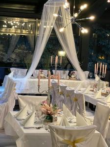 a table set up for a wedding with white linens and candles at Parkhotel Waldschlösschen in Annaberg-Buchholz
