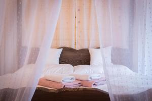 a bed with white curtains and towels on it at Vila Kotlina - High Tatras 2023 in Vysoké Tatry