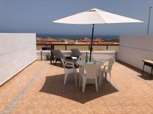 a patio with a table and chairs and an umbrella at Alojamientos Vistas Edén 67 in Caleta De Fuste