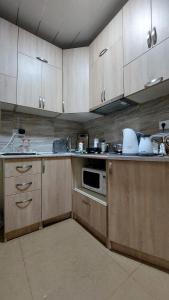 a kitchen with wooden cabinets and a sink and a microwave at Apart Hotel Vera in Tbilisi City