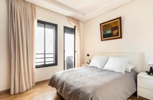 a white bedroom with a bed and a window at SUITE APPARTEMENT BOURGOGNE 2 pièces in Casablanca