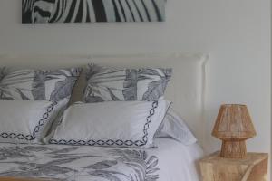 a bed with gray and white pillows and a lamp at Chambre d'hôtes A Vadina Porticcio in Porticcio