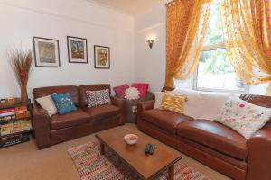 a living room with brown leather couches and a table at Upton House - Charming 4-bedroom home in Torquay in Torquay