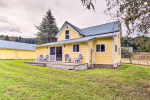 a yellow house with chairs on a large yard at Quaint Coquille Getaway Near Beaches and Parks! in Coquille