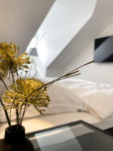 um vaso com flores amarelas numa mesa de vidro ao lado de uma cama em Ferienwohnung am Alexbad em Bad Alexandersbad
