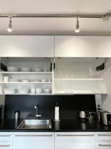 a kitchen with white cabinets and a sink and dishes at Ferienwohnung am Alexbad in Bad Alexandersbad